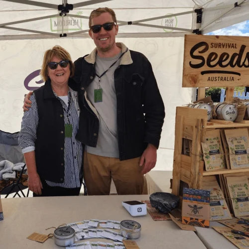 man and woman smiling beside seed australia small stand