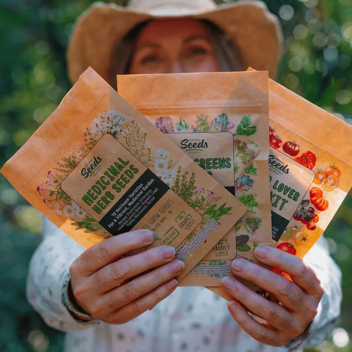 Medicinal herb seeds packets held by a person in a garden setting.